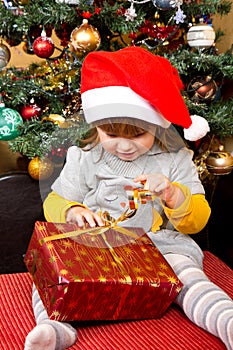 Happy child in Santa hat opening Christmas gift box