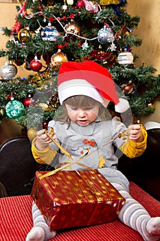 Happy child in Santa hat opening Christmas gift box