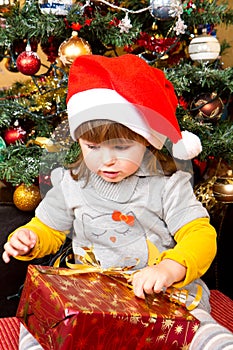 Happy child in Santa hat opening Christmas gift box