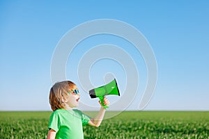 Happy child shouting through loudspeaker against blue summer sky