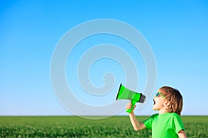 Happy child shouting through loudspeaker against blue summer sky