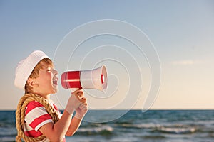 Happy child shouting through loudspeaker on summer vacation