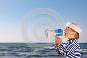 Happy child shouting through loudspeaker on summer vacation