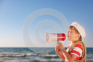 Happy child shouting through loudspeaker on summer vacation