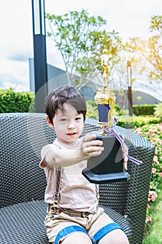 Happy child showing trophy Excited young boy win a competition of sport Adorable kid proud of himself and celebrating of victory