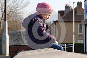 Happy Child Sitting on a Parapet and Smiling