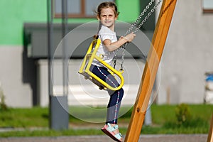 Happy child sitting on a seesaw at playground on a sunny summer day