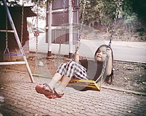 Happy child sitting swinging on swing at outdoor