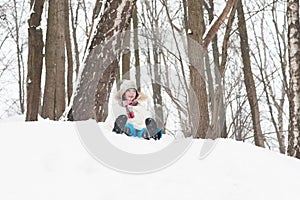 Happy child sledging from a snowy hill