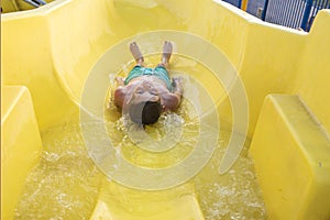 happy child slides down the yellow water slide in the water park.