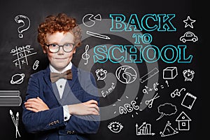 Happy child smart student boy in classroom on chalkboard background. Back to school concept