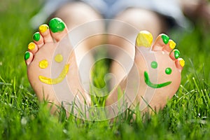 Happy child with smile on feet lying on green spring grass