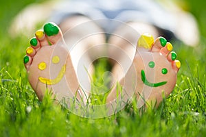 Happy child with smile on feet lying on green spring grass