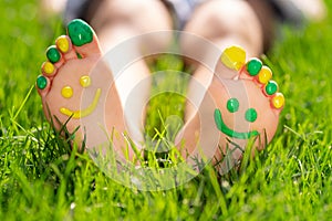 Happy child with smile on feet lying on green spring grass