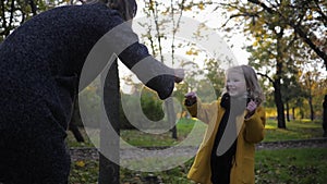 Happy child, smiling little girl having fun with her mother in game of stone scissor paper while walking in the autumn