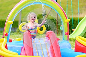 Happy child splashing in inflatable garden pool