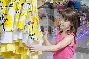 A happy child in a store chooses a dress. Shopping