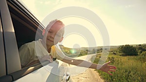 Happy child stretched out his hand from the car window. Happy family. Child hand plays with the wind. Free kid waving
