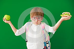 Happy child student against green chalkboard