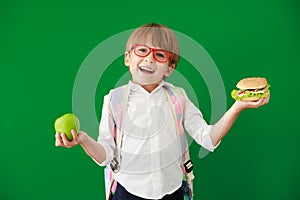 Happy child student against green chalkboard