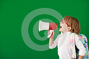 Happy child student against green chalkboard