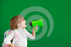 Happy child student against green chalkboard