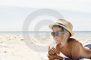 Happy child in sunglasses and hat on beach. Summer vacation concept