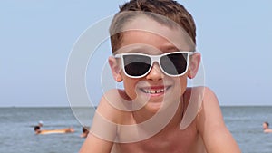 A happy child in sunglasses. Portrait of a laughing boy on the beach. A happy family. Journeys. summer vacations