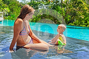Happy child swimming in pool with mother