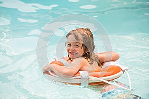 Happy child with swimming ring. Summer party in pool. Kid in swimmingpool. Boy having fun at aquapark.