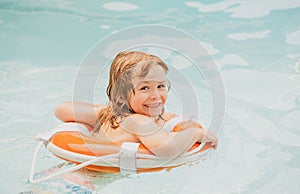 Happy child with swimming ring. Summer party in pool. Kid in swimmingpool. Boy having fun at aquapark.