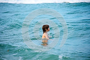 Happy child swimming in sea. Kid boy having fun on the beach. Kids summer vacation.