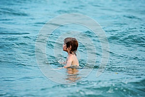 Happy child swimming in sea. Kid boy having fun on the beach. Kids summer vacation.