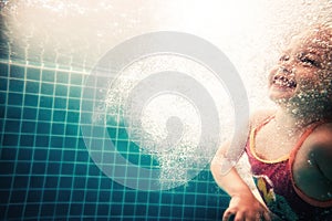 Happy child swimming underwater in swimming pool during diving training