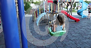 Happy child swings on swing on summer day