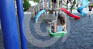 Happy child swings on swing on summer day