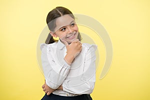 Happy child thinking on yellow background. Little daydreamer girl with cute smile. Lost in thoughts. Your dreams can