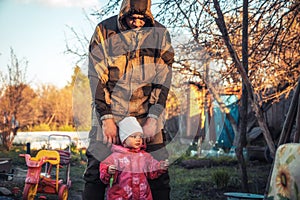 Happy child toddler learning walking with father outdoors on backyard playground in countryside