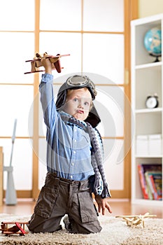 Happy child toddler playing with toy airplane and dreaming of becoming a pilot