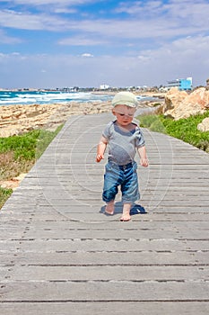 A happy child walks along the path on the nature by the sea