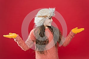 Happy child in warm winter clothes of knitted sweater and gloves with earflap hat ready for holiday activity, cold