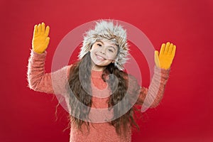 Happy child in warm winter clothes of knitted sweater and gloves with earflap hat ready for holiday activity, winter