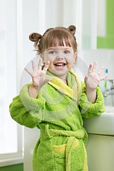 Happy child washing hands and showing soapy palms