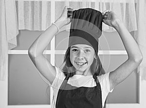 happy child wear cook uniform. chef girl in hat and apron. kid cooking food in kitchen. choosing a career. little helper