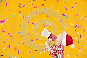 Happy child wearing Santa Claus costume speaking by megaphone