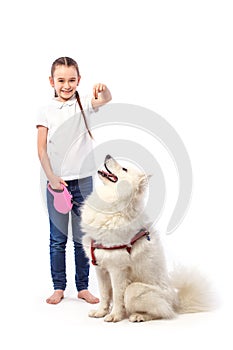 Happy child with white dog. Portrait girl with eating pet. Smilyng Samoyed Laika dog.