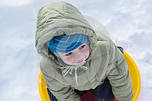 Happy child in winterwear laughing while playing in snowdrift