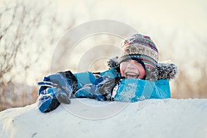 Happy child in winterwear laughing while playing in snowdrift