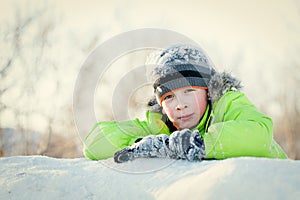 Happy child in winterwear smiling while playing in snowdrift