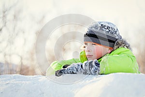 Happy child in winterwear smiling while playing in snowdrift